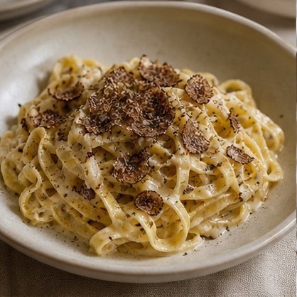 Tagliatelle in a cream ceramic bowl topped with fresh truffle